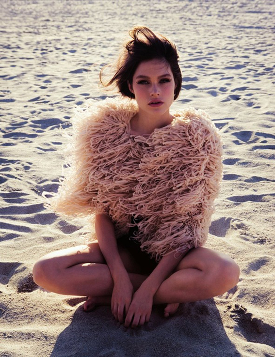 girl with a feather coat on the beach